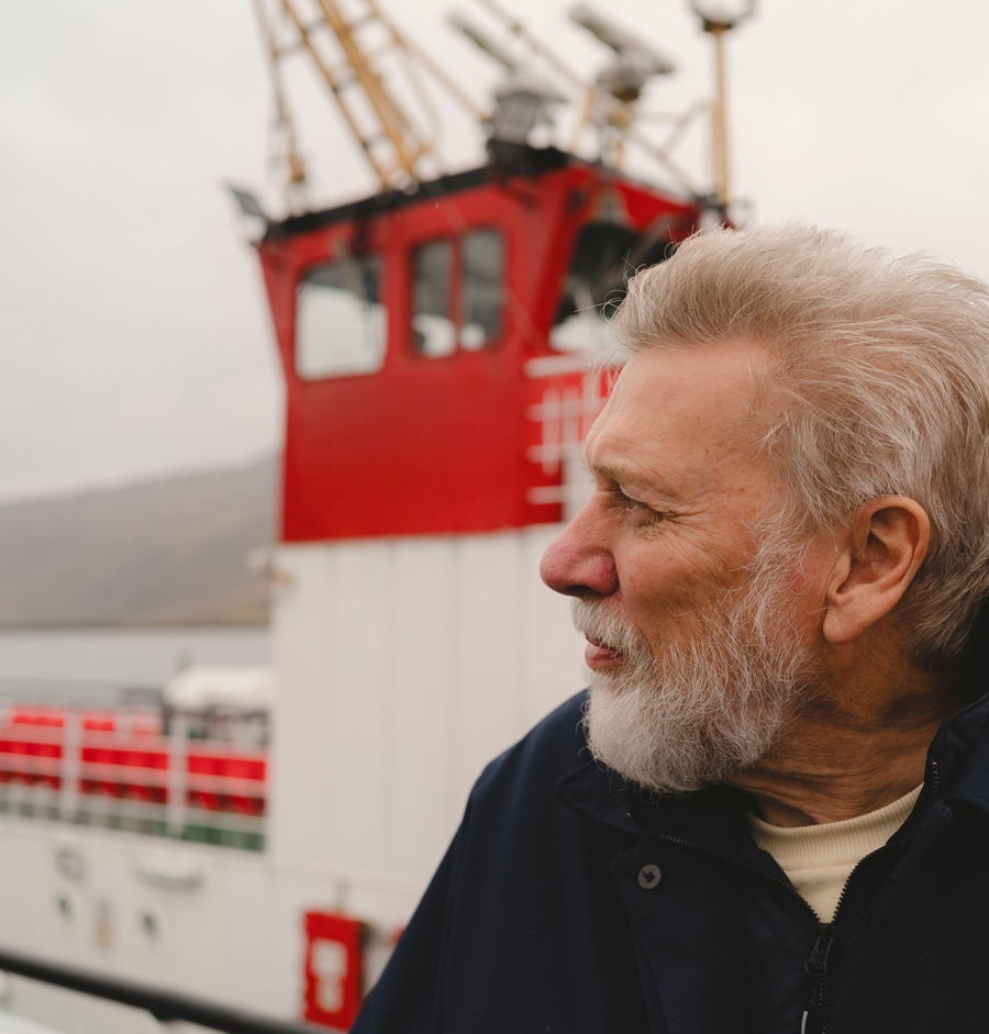 Thoughtful senior man looking away with ferry boat in background at harbor