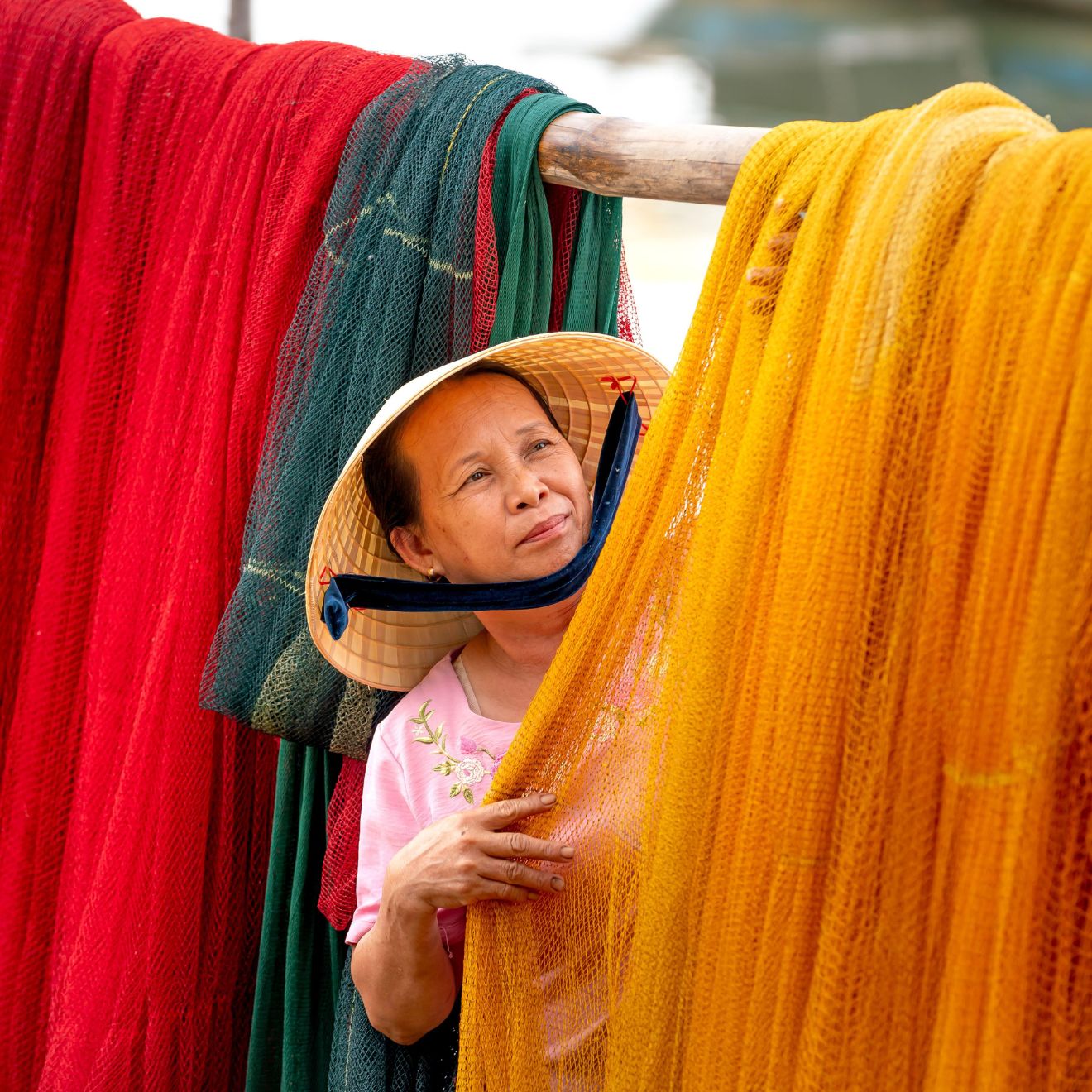 Thua Thien Hue Province, Vietnam - May 1, 2022: A woman in a fishing village exposing colorful nets after fishing trips to the sea - Image ID: 2JBKT6R (RF)