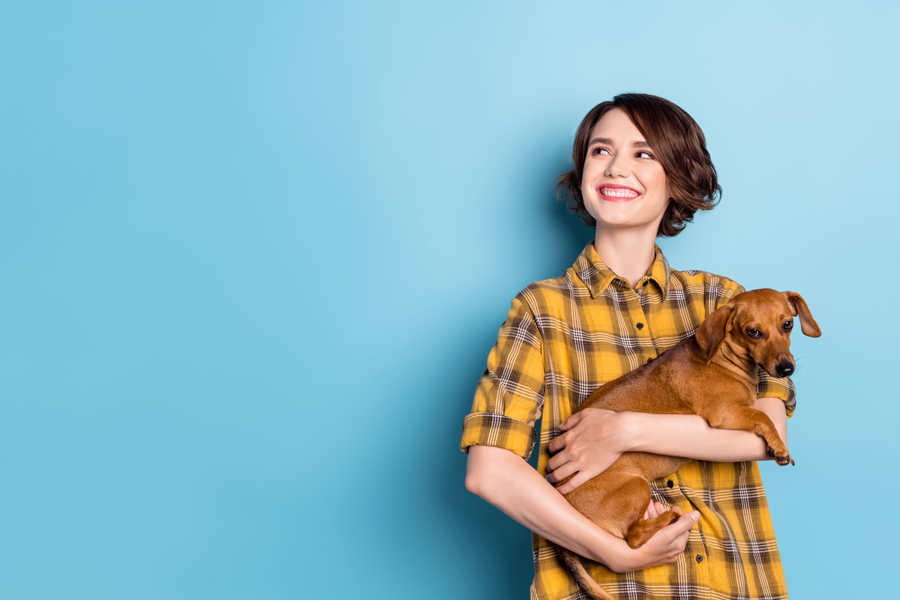 Young woman looking up into empty space while cuddling dachshund dog 