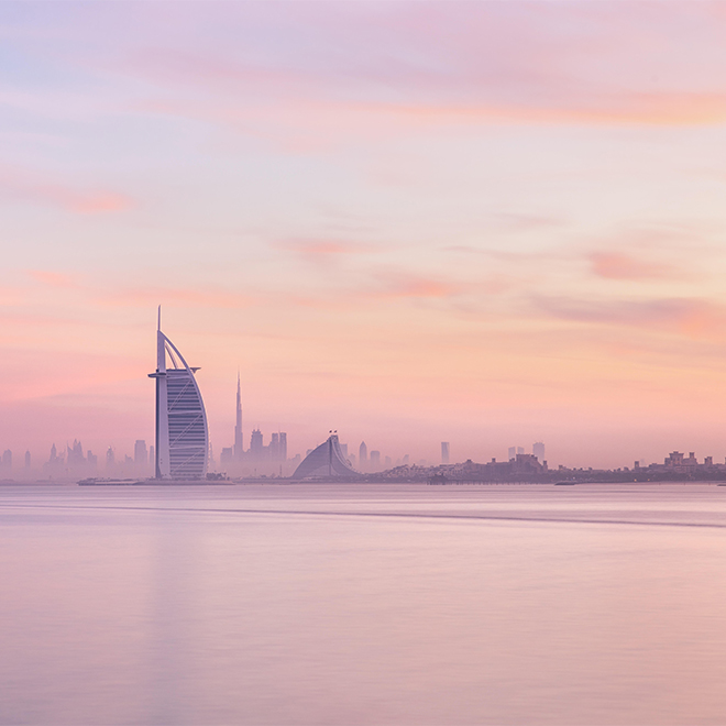 Vista mozzafiato sulla skyline di Dubai dalla spiaggia di Jumeirah al Downtown illuminato da caldi colori pastello all'alba. Dubai, Emirati Arabi Uniti.