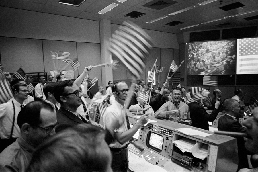 Overall view of the Mission Operations Control Room at the Manned Spacecraft Center, showing the flight controllers celebrating the successful conclusion of the Apollo 11 lunar landing mission on July 24, 1969