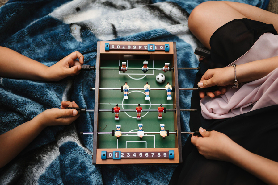 two people playing mini table football on a bed