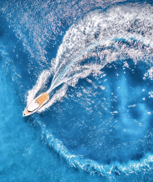 Aerial view of the speed boat in transparent blue water at sunset
