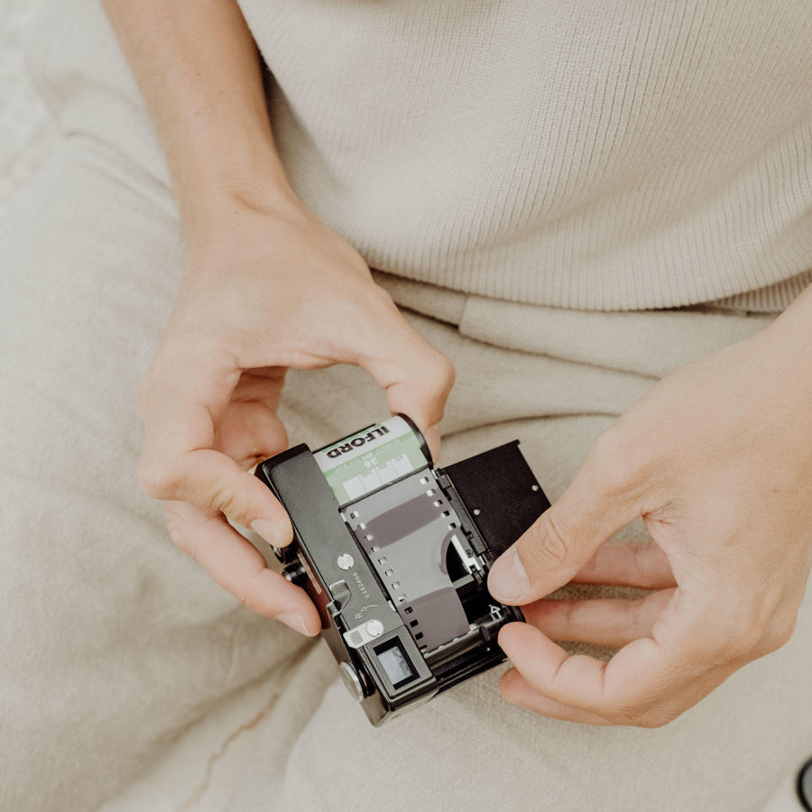 vintage photography process with hands loading film roll into classic camera