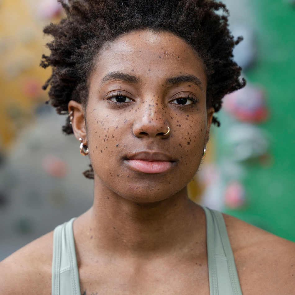 Portrait of serious woman looking at camera in front of climbing wall