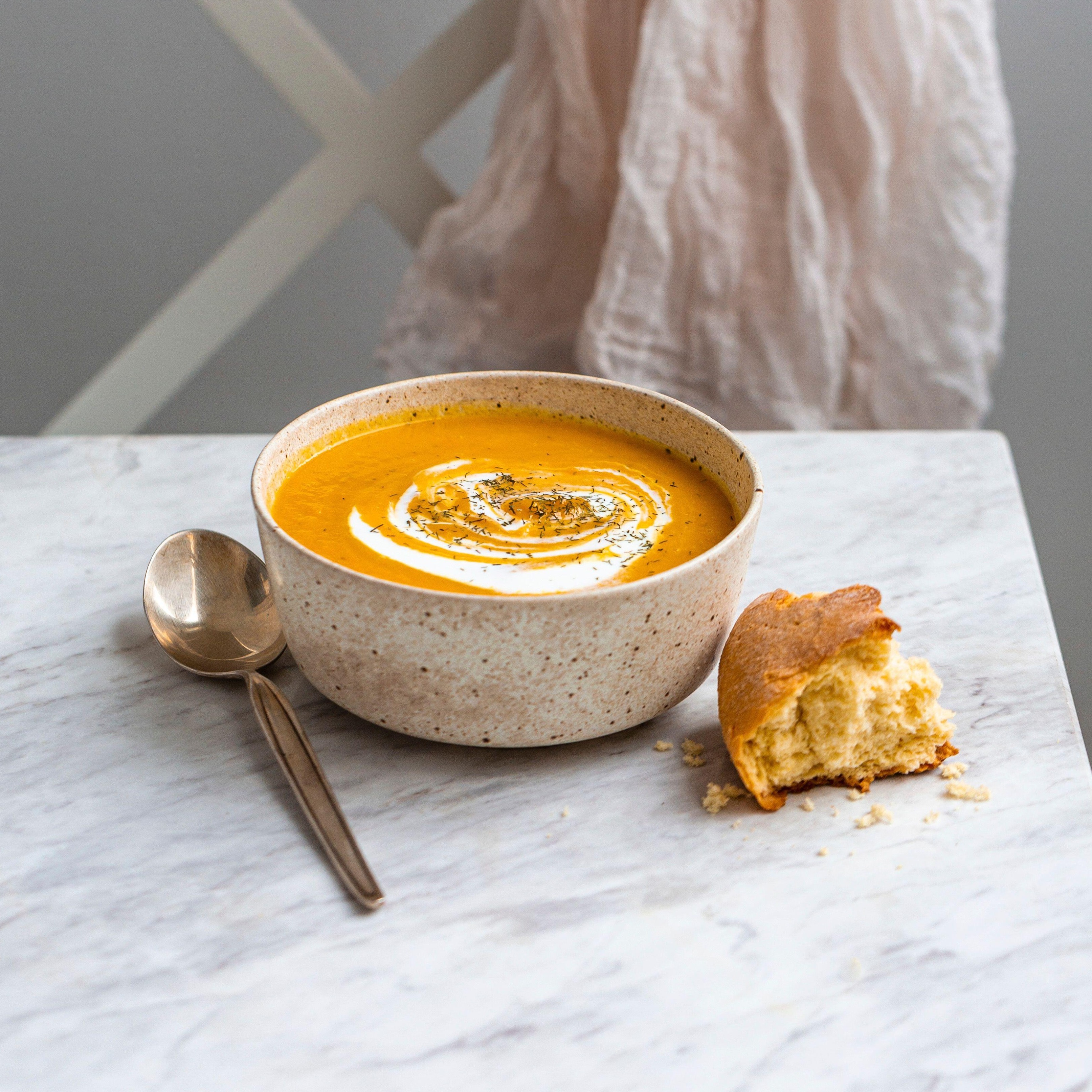 Bowl of pumpkin soup on a white marble surface