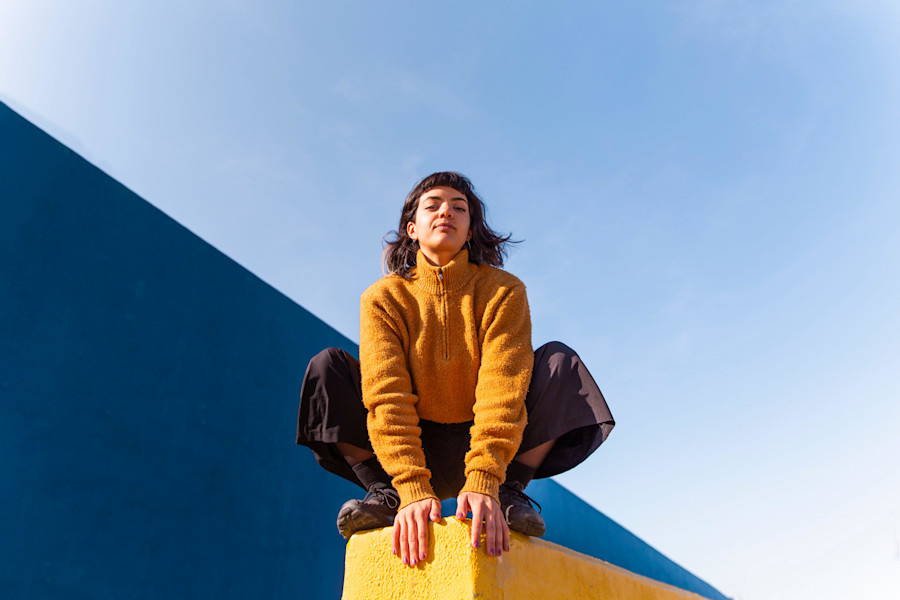 Young woman crouching on wall