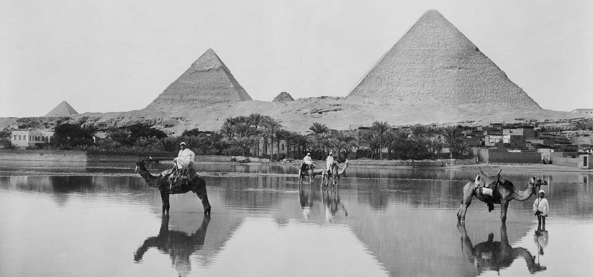 Männer und Kamele im flachen Hochwasser vor dem Hintergrund der Pyramiden, Ägypten, 1890.