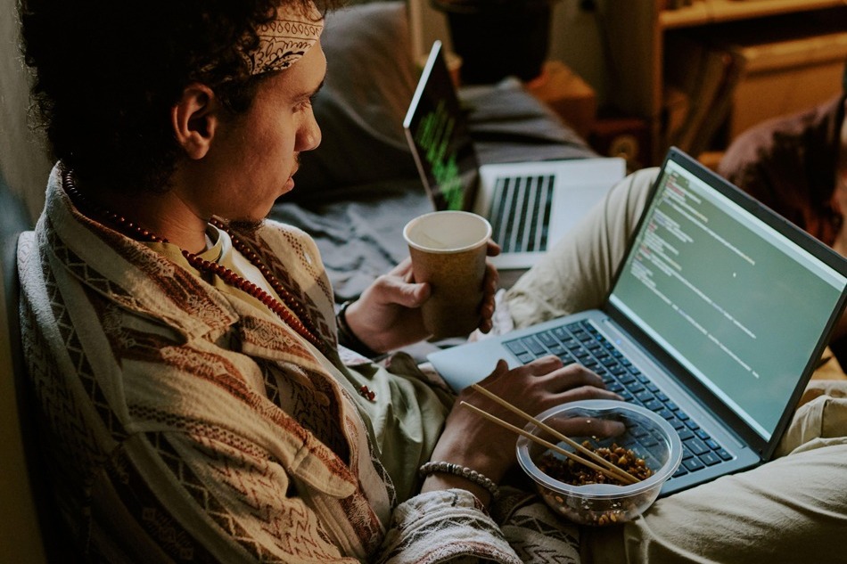 Plan en plongée de jeunes startupers mangeant des nouilles et vérifiant les codes terminés pendant la pause