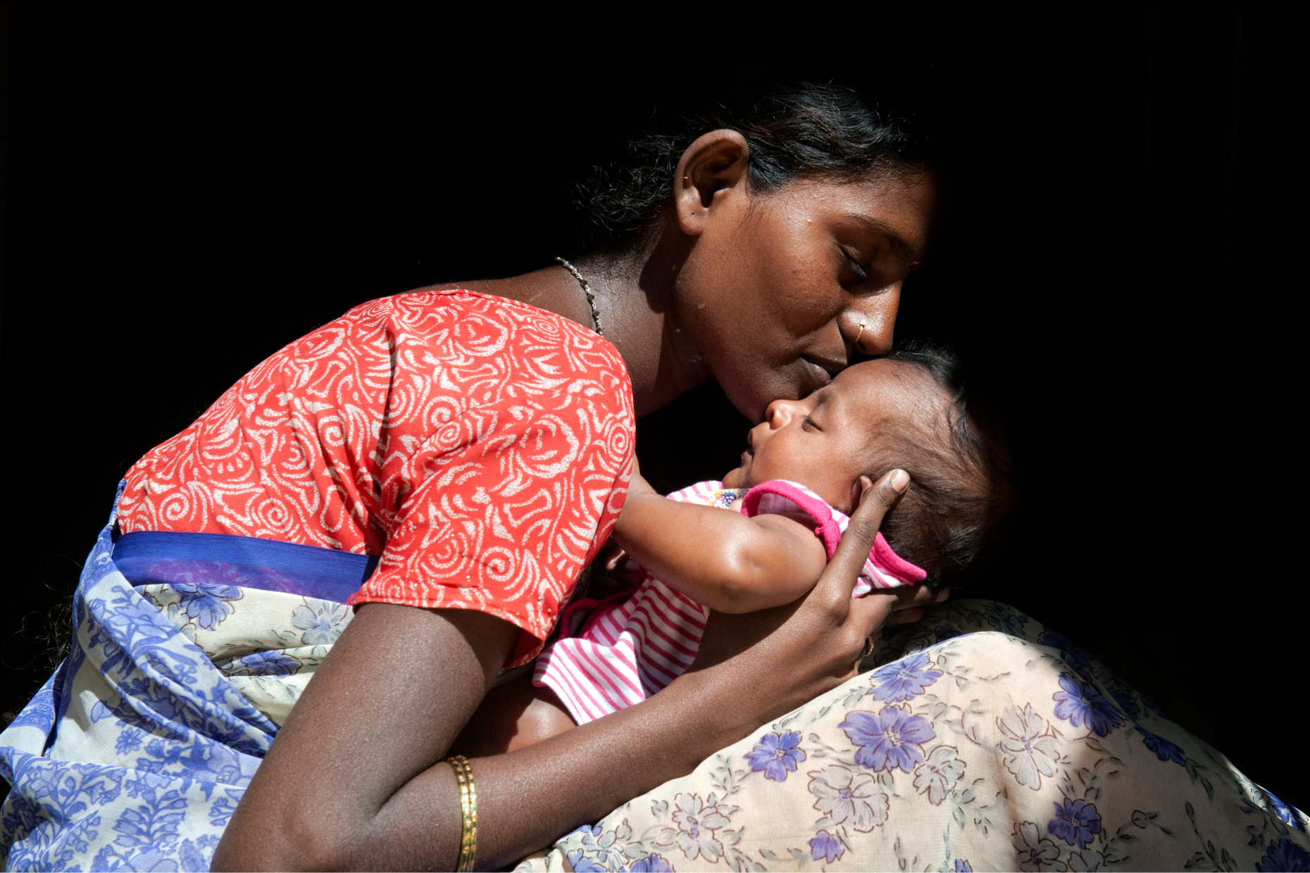 Giovane madre del sud dell'India che culla il suo neonato.