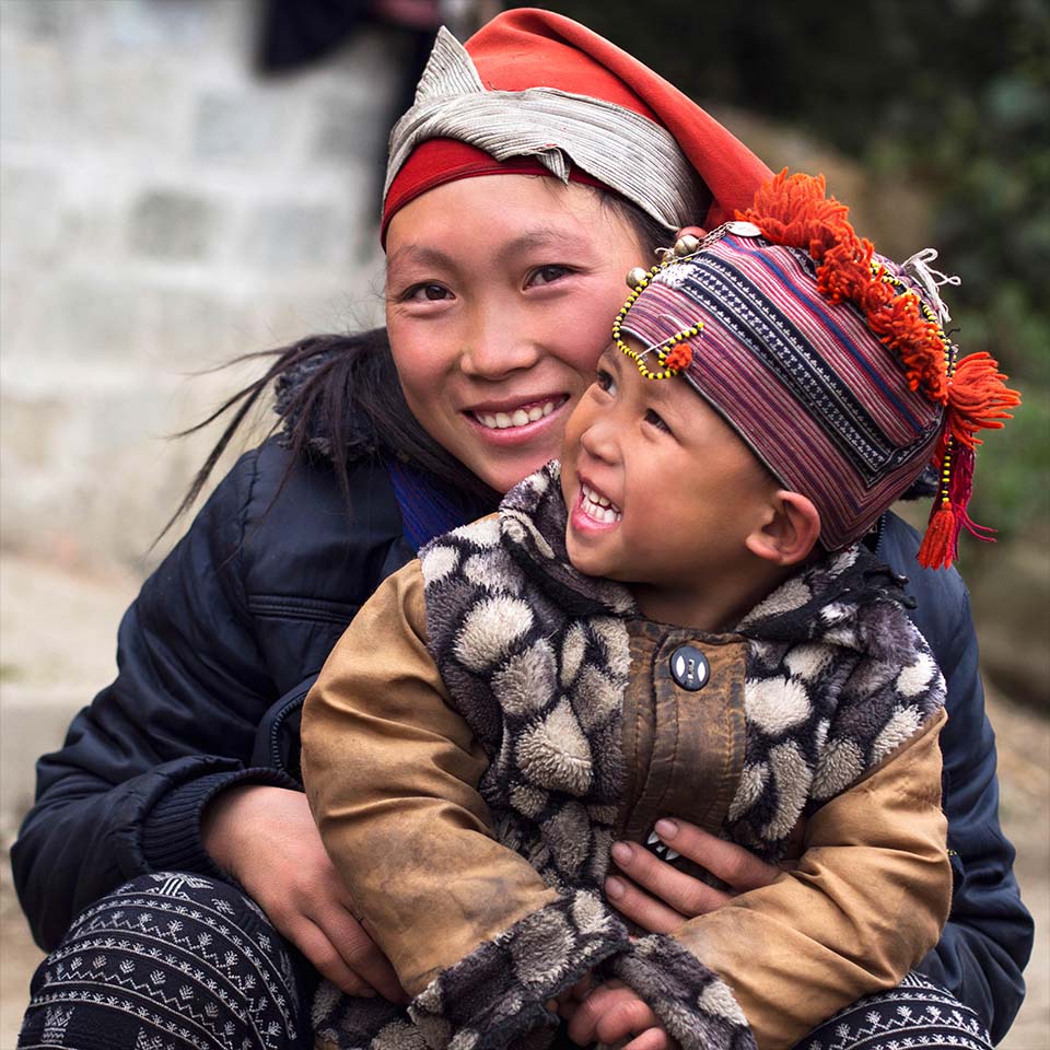 E9R0GC – Glückliche Hmong-Frau und Kind sitzen lächelnd im Freien im Dorf Giang Ta Chai in der Nähe der Stadt Sapa, Provinz Lao Cai, Vietnam