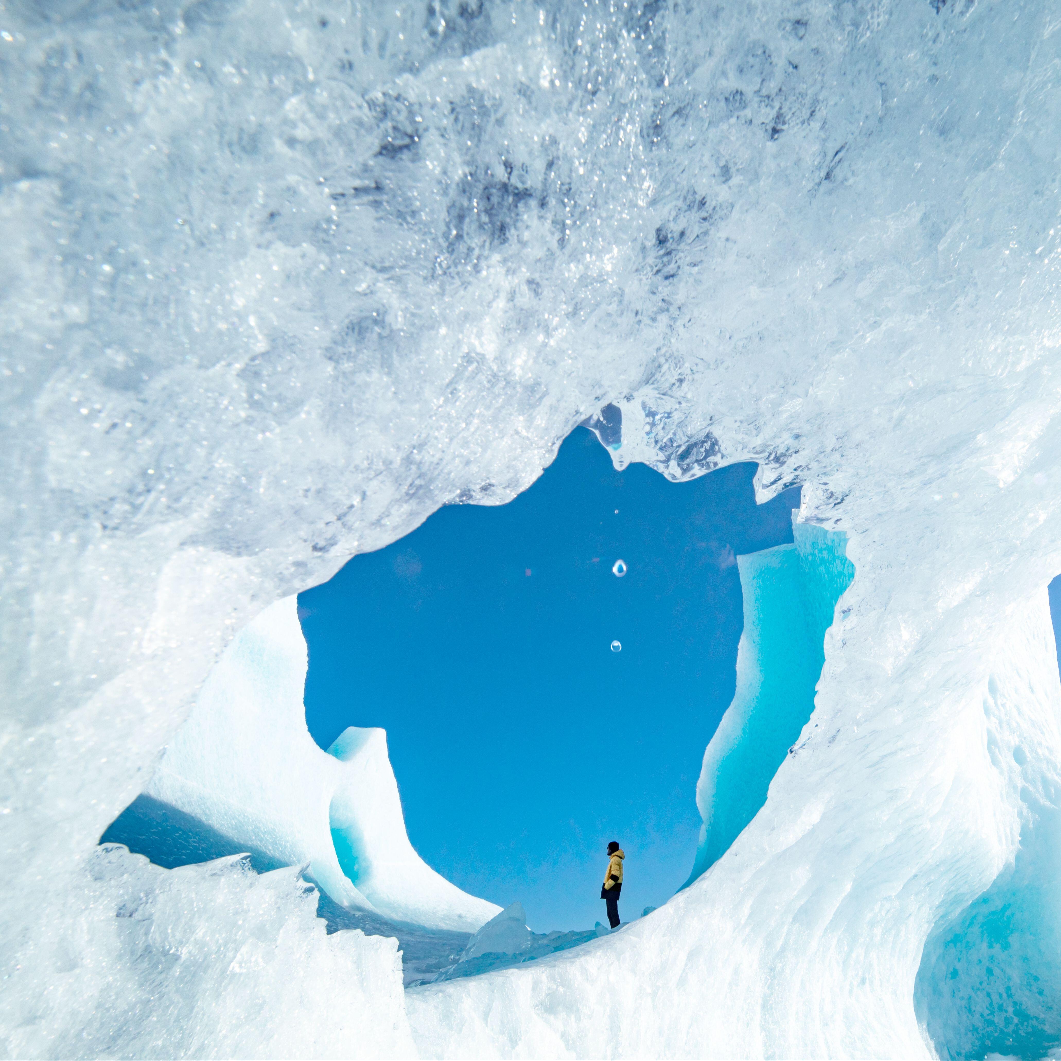 traveler hiker admiring spectacular scenery of frozen seashore with ice and snow in winter in Iceland