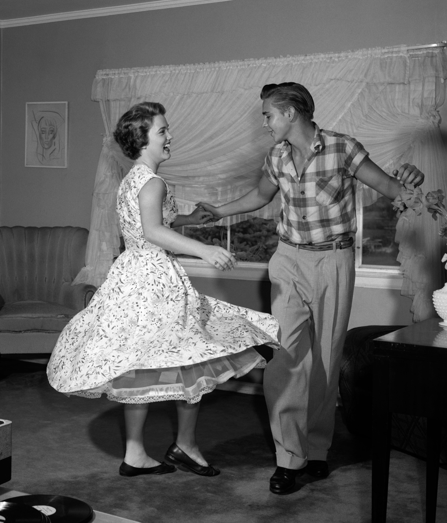 1950s teen couple dancing jitterbug in living room