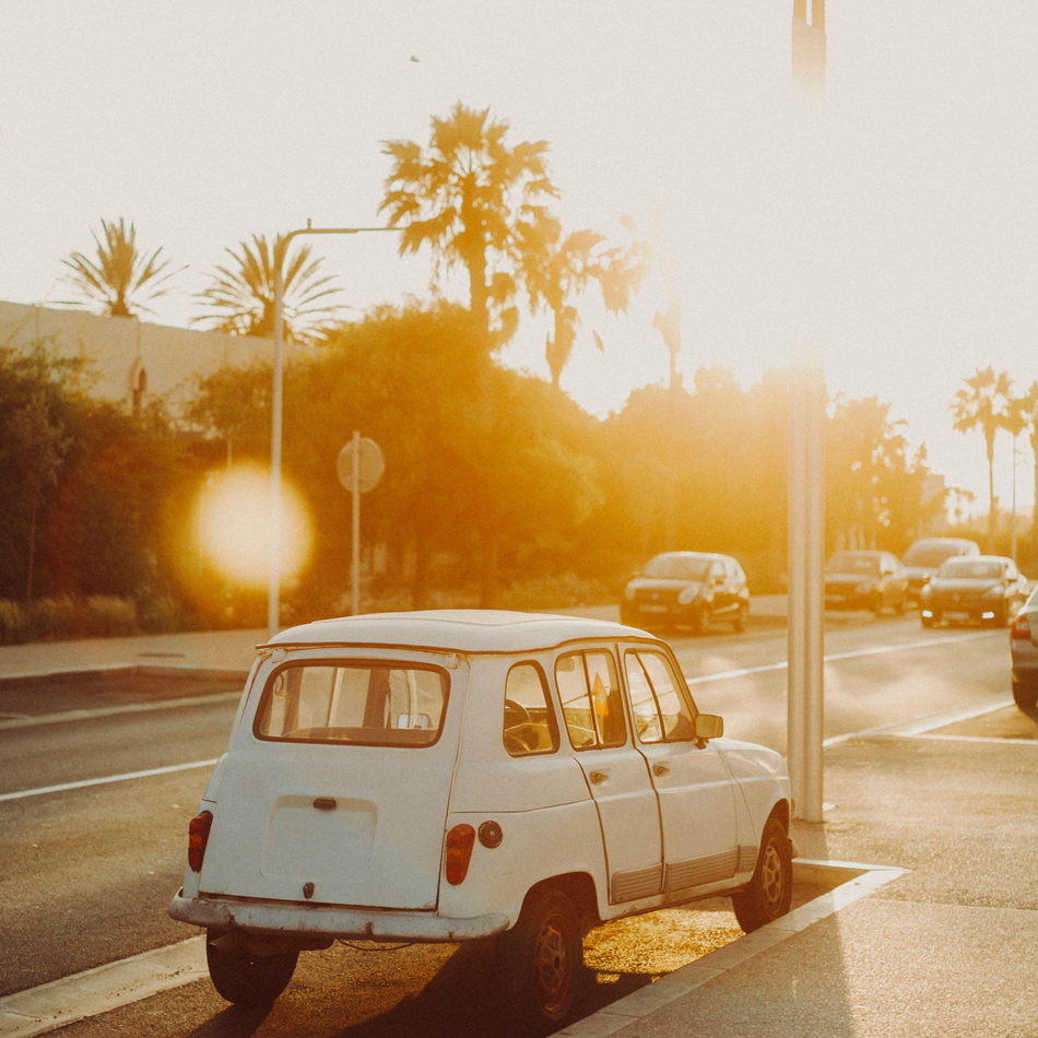 A vintage white car is backlit by the setting sun in Morocco