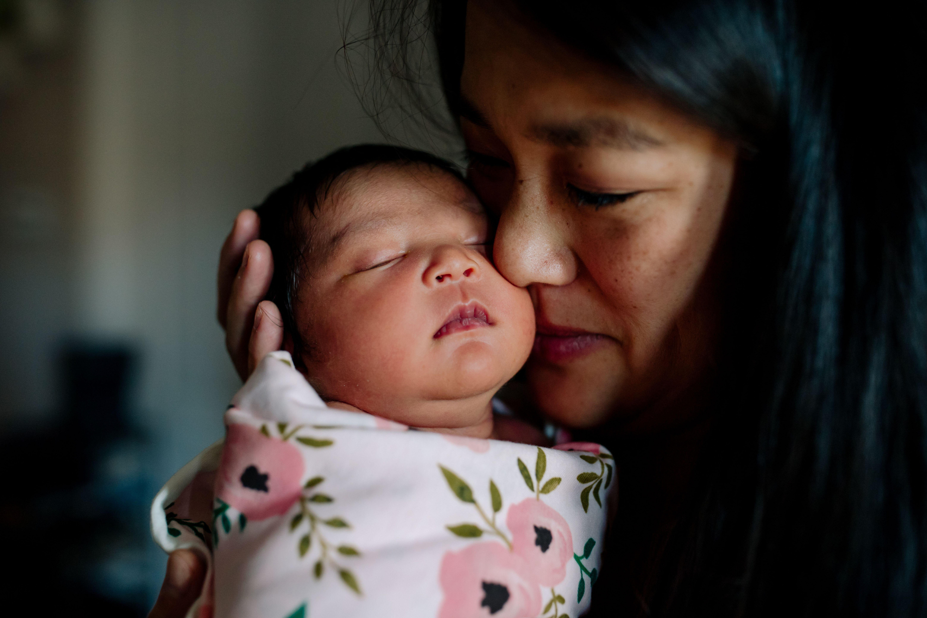 Una madre tiene teneramente il suo neonato contro il suo viso.