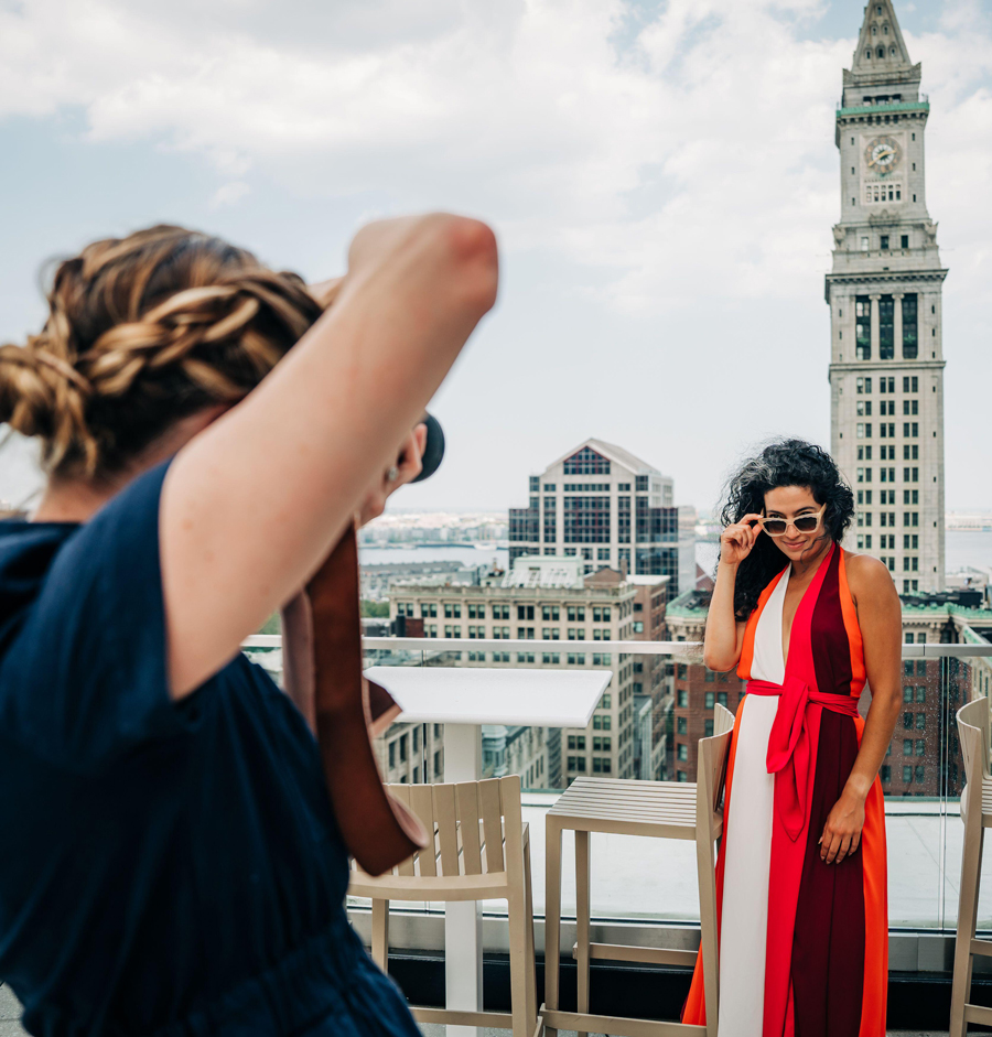 Woman poses for rooftop photoshoot with Boston skyline view