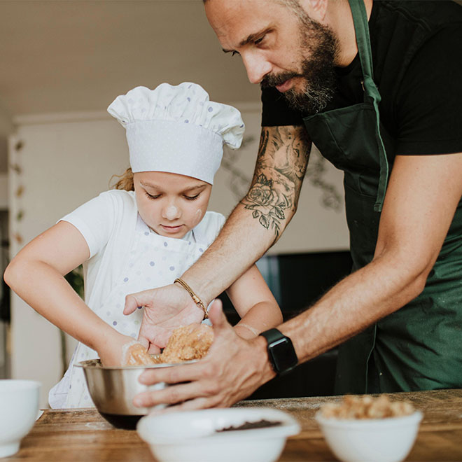 Father and daughter baking cookies at home.
