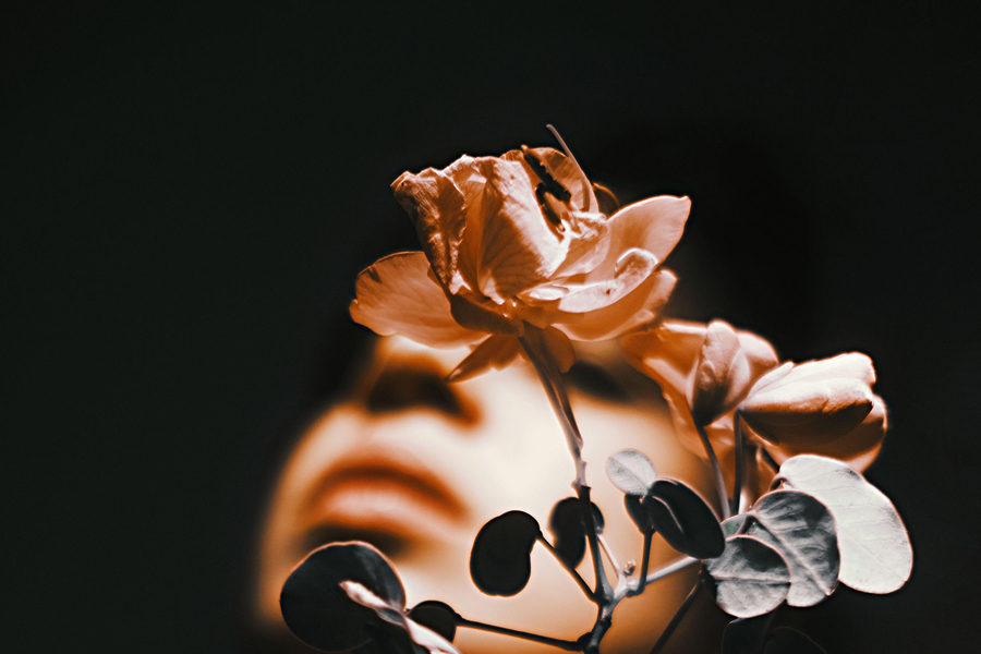 Creative studio shot of woman standing behind flower